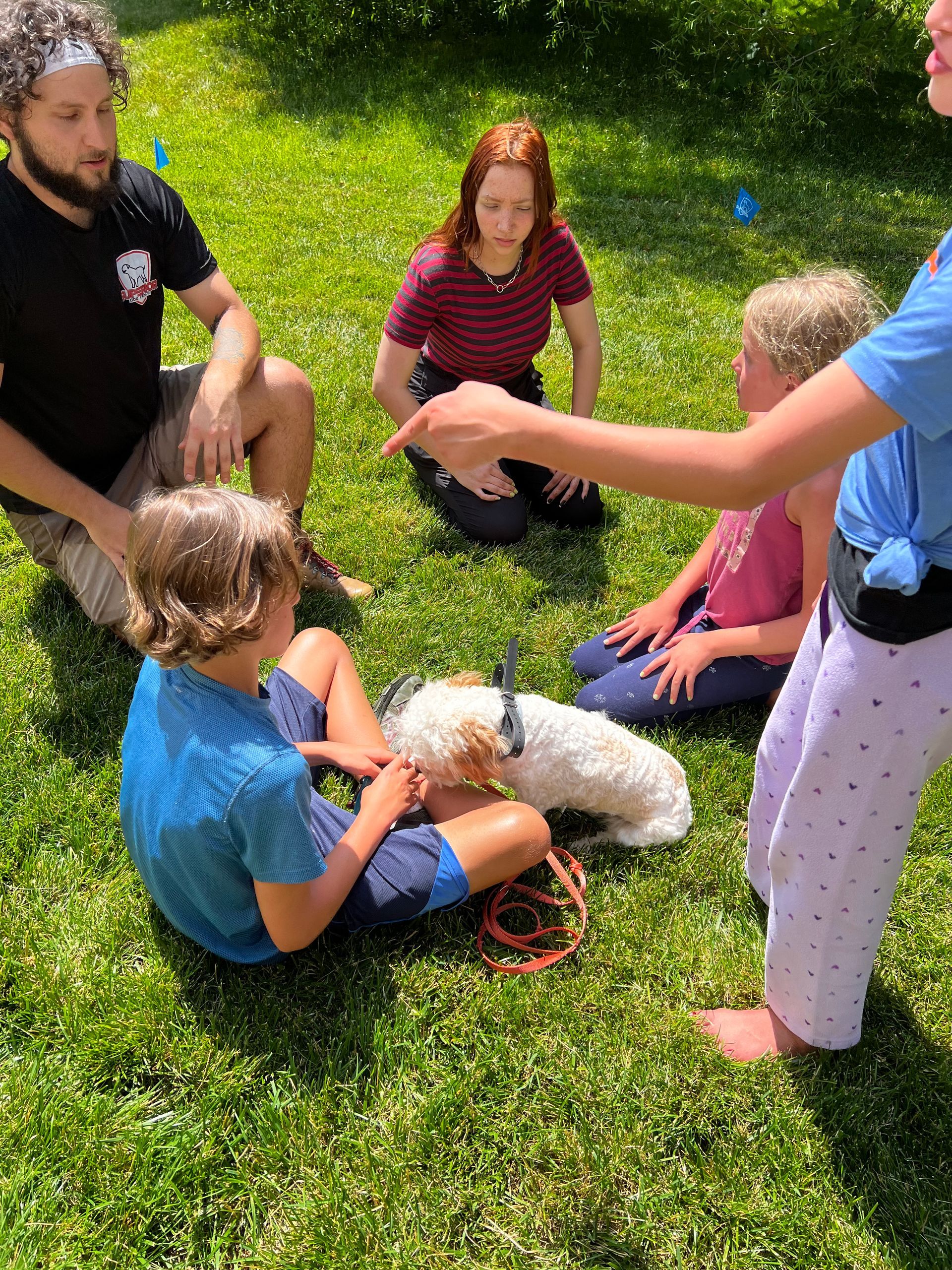 A group of people are sitting on the grass with a dog.