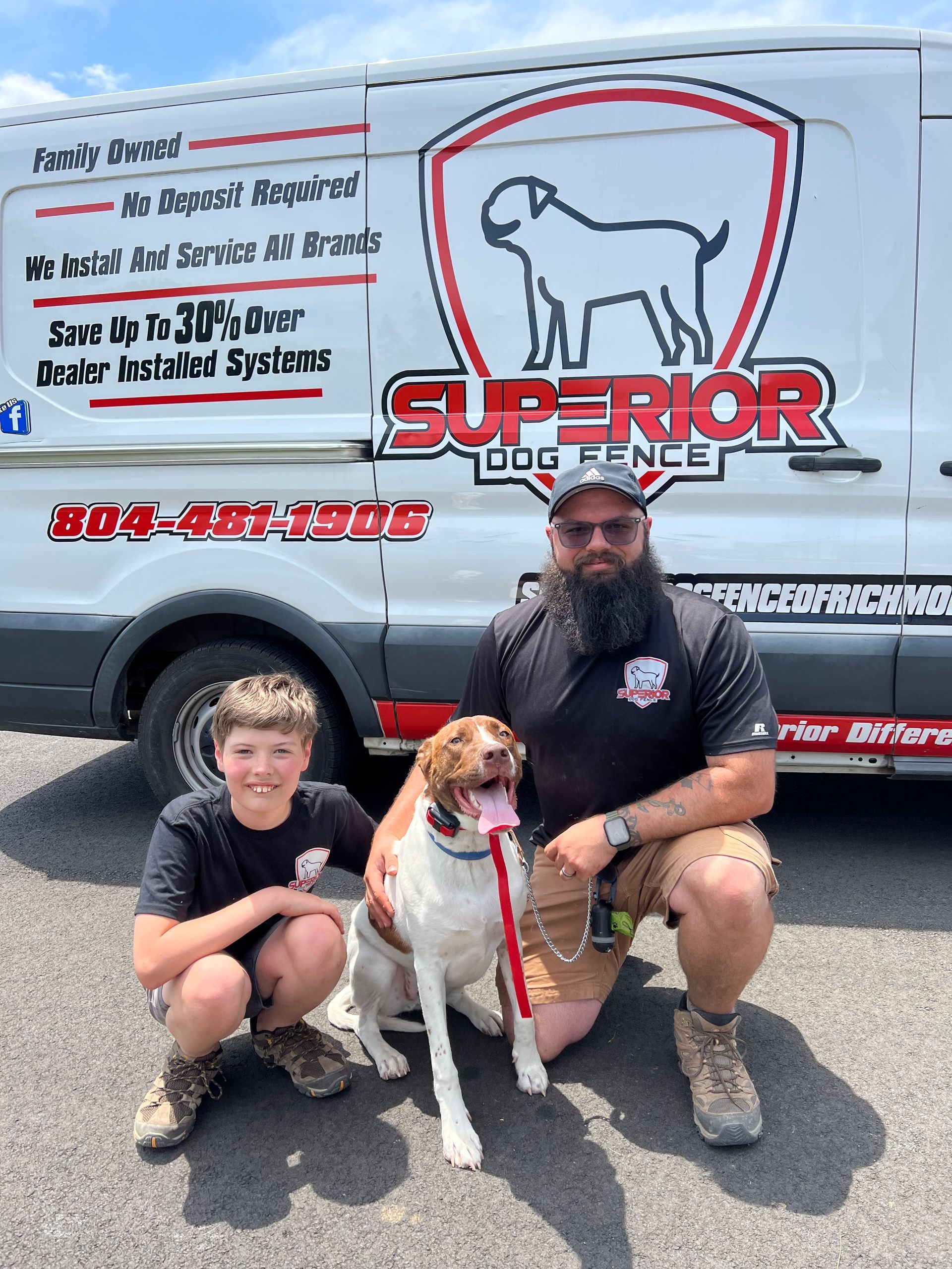 A man, boy, and dog kneel in front of a Superior Dog Fence van.