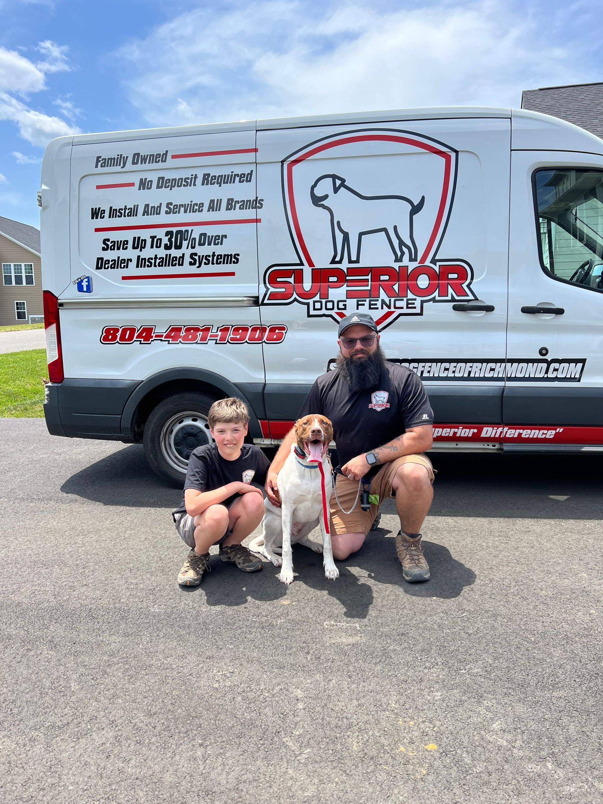 A woman is kneeling down and hugging a dog in the grass.