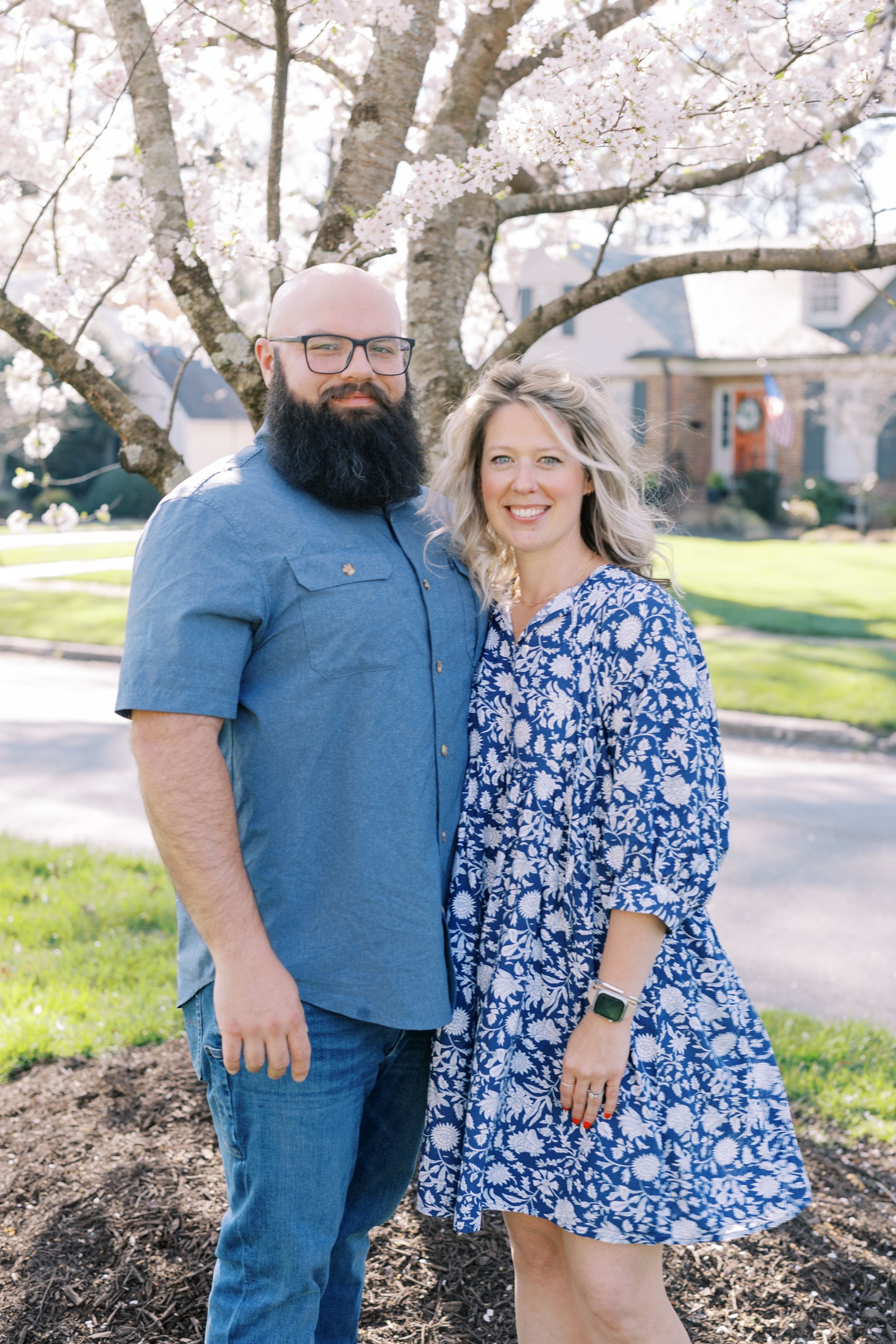 We can keep big and small dogs safe with Superior Dog Fence technology! couple poses under a tree. Father with beard, mother in blue dress.