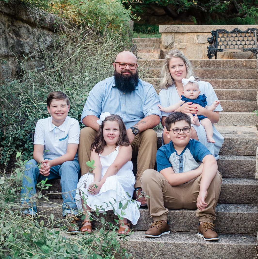 A family is sitting on the steps of a house.