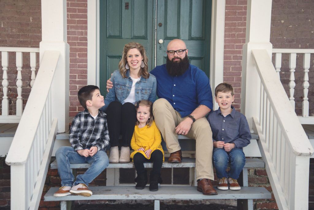 A family is sitting on the steps of a house.