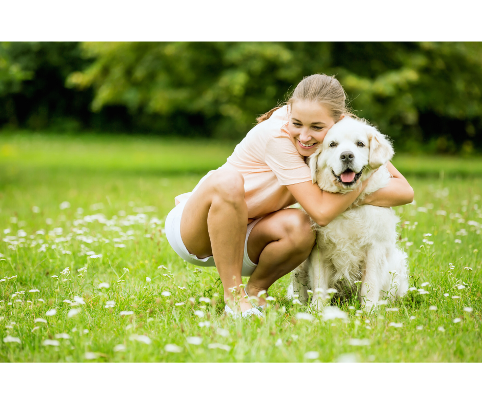 A woman is hugging a dog in a field of flowers.