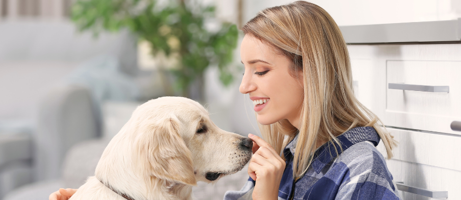 A woman is petting a dog in a kitchen.