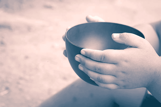 A child is holding an empty bowl in their hands.