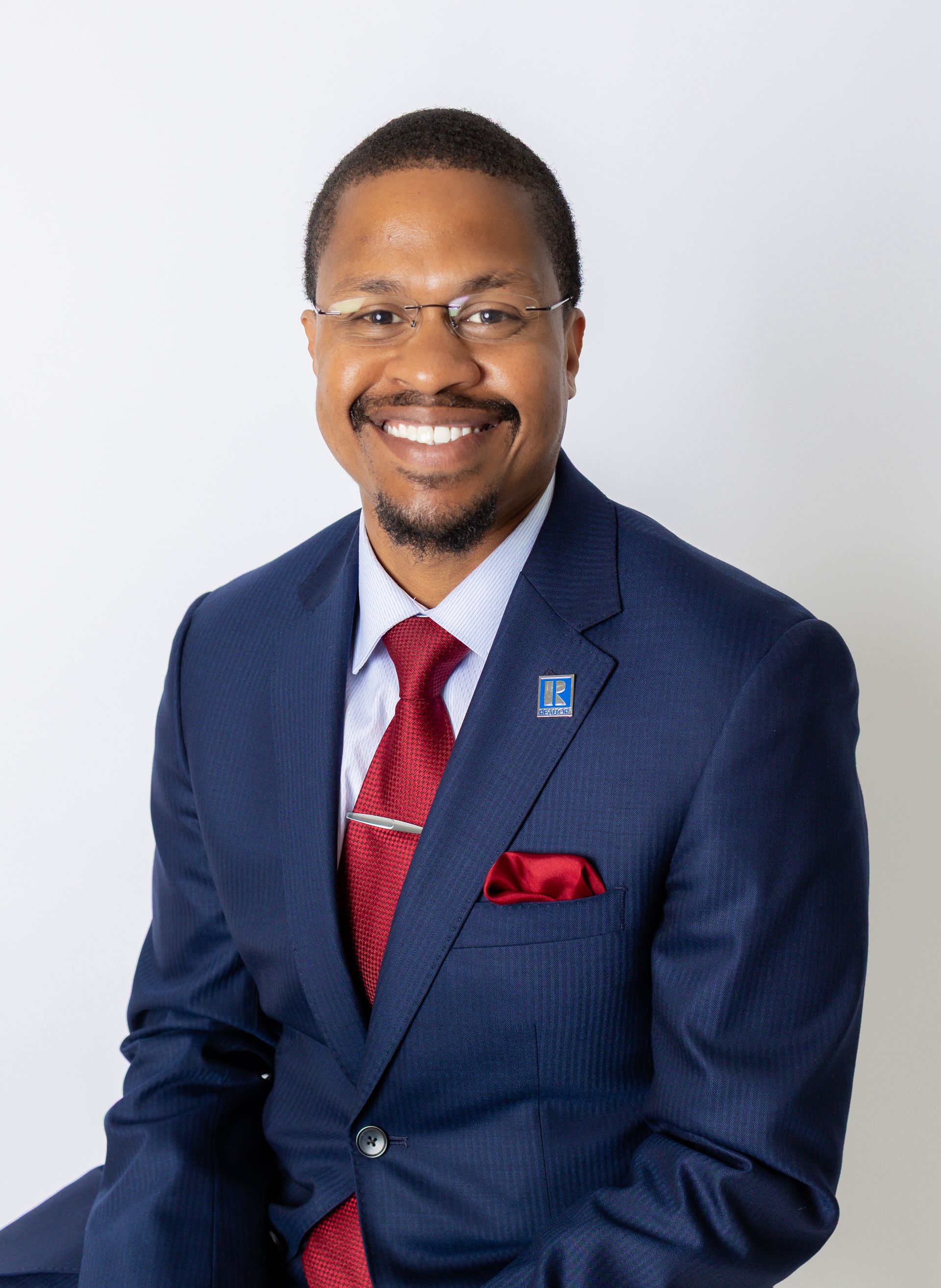 A woman is sitting at a desk with a laptop and a vase of flowers.