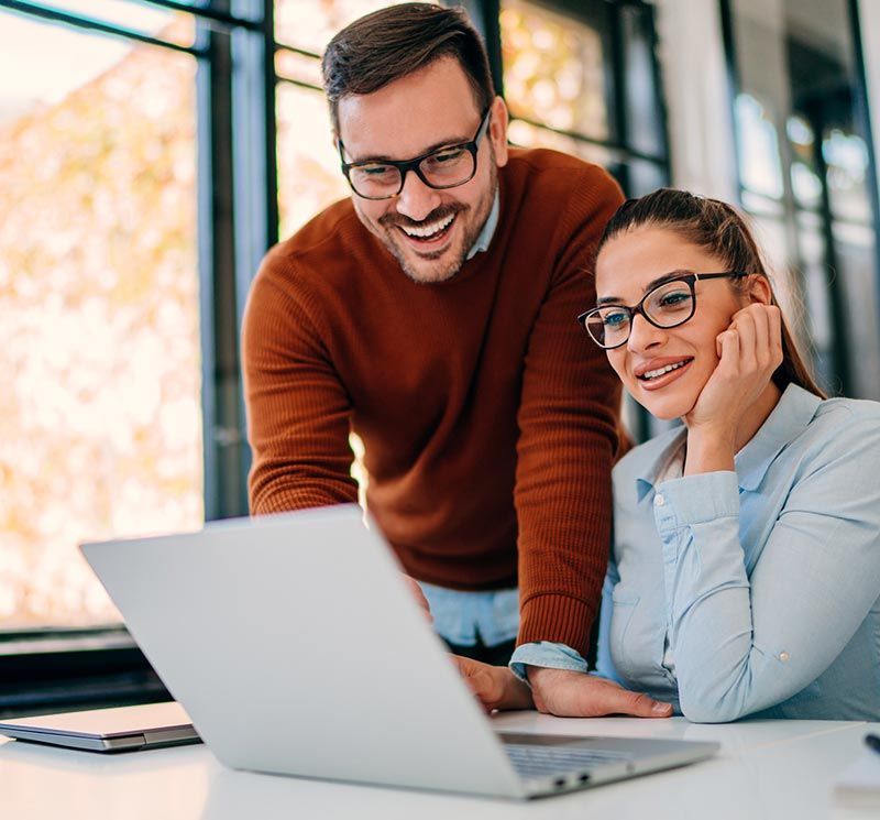 A man and a woman are looking at a laptop computer.
