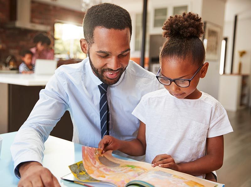 A man and a little girl are reading a book together.