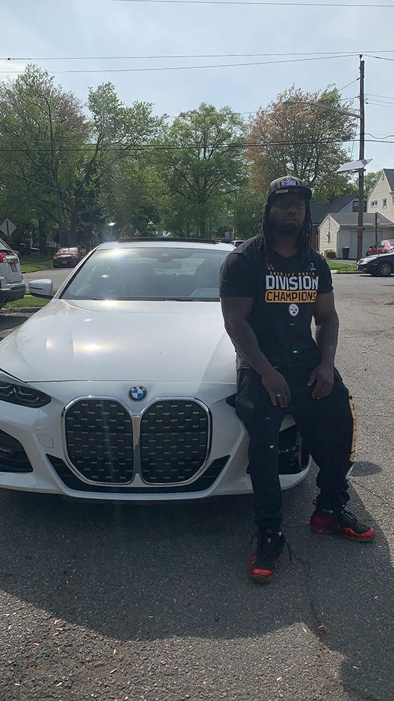 A man is sitting on the hood of a white bmw.