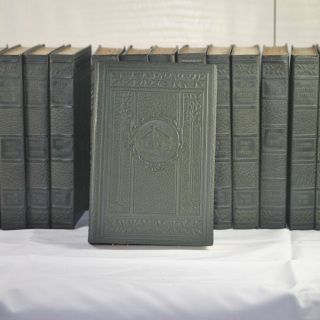A row of books are lined up on a table with a gray book in the middle