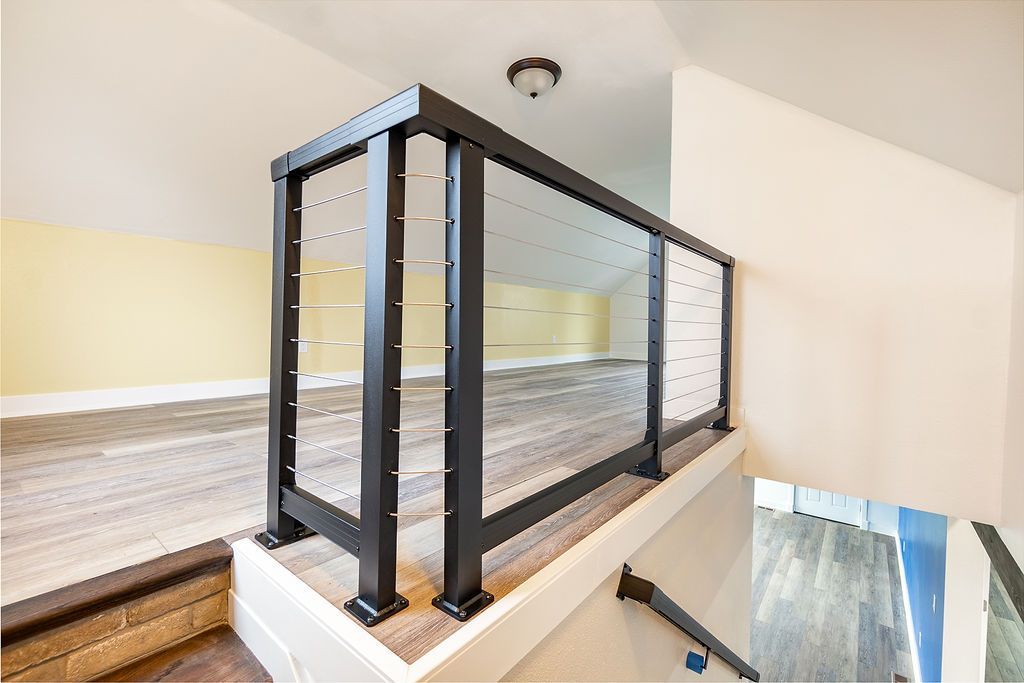 Black metal railing with glass panels on a landing, with stairs visible.