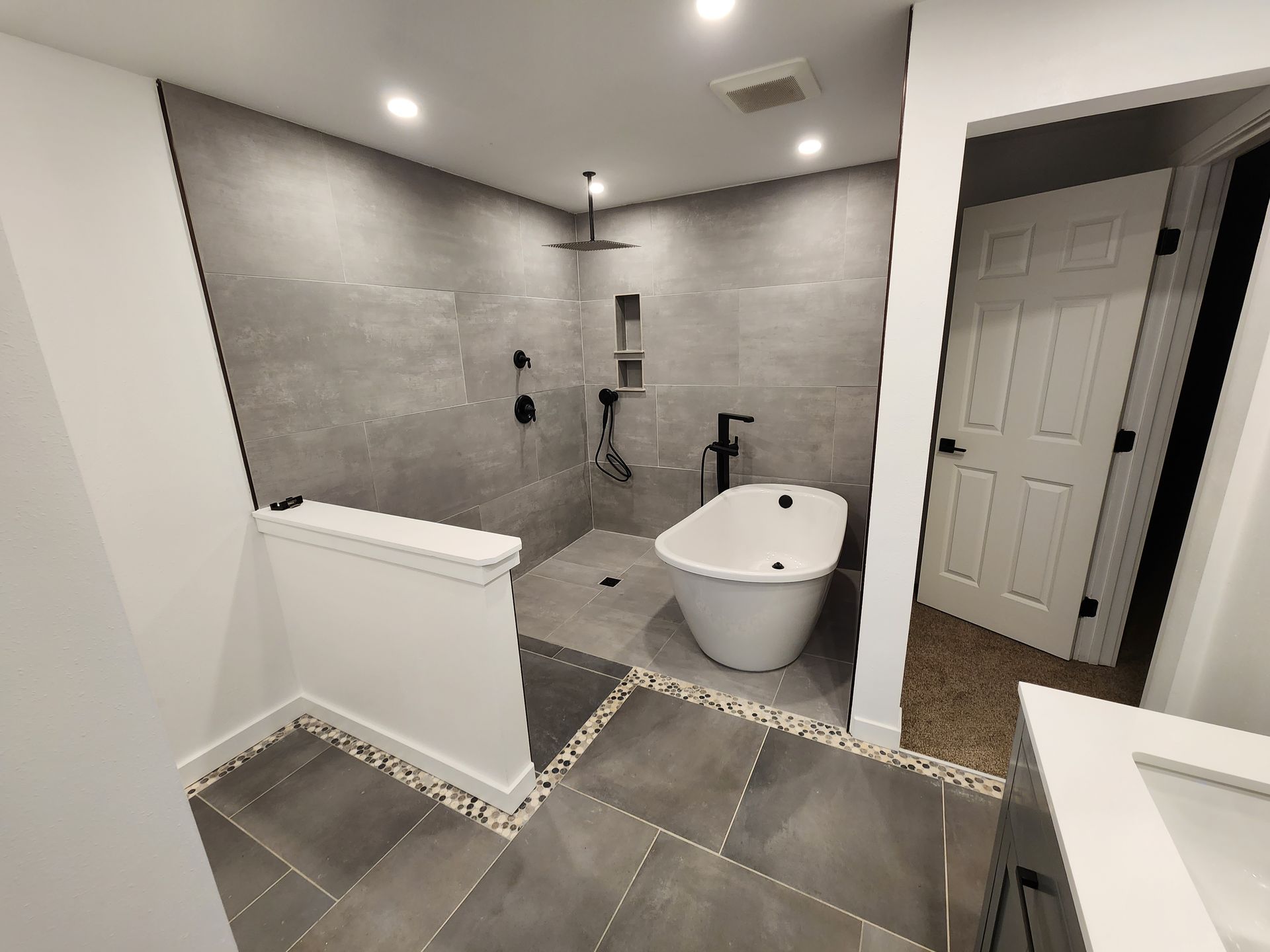 Modern bathroom with gray tile, freestanding tub, and walk-in shower.
