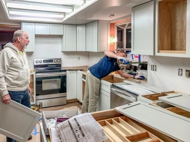 Two men are working on a kitchen remodel.