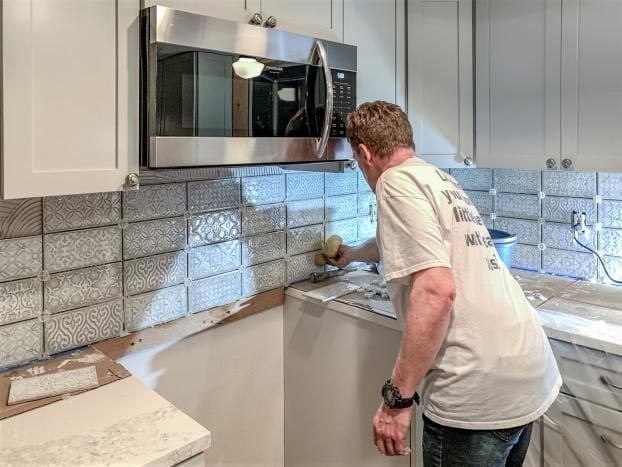 A man is cleaning a kitchen counter with a sponge.