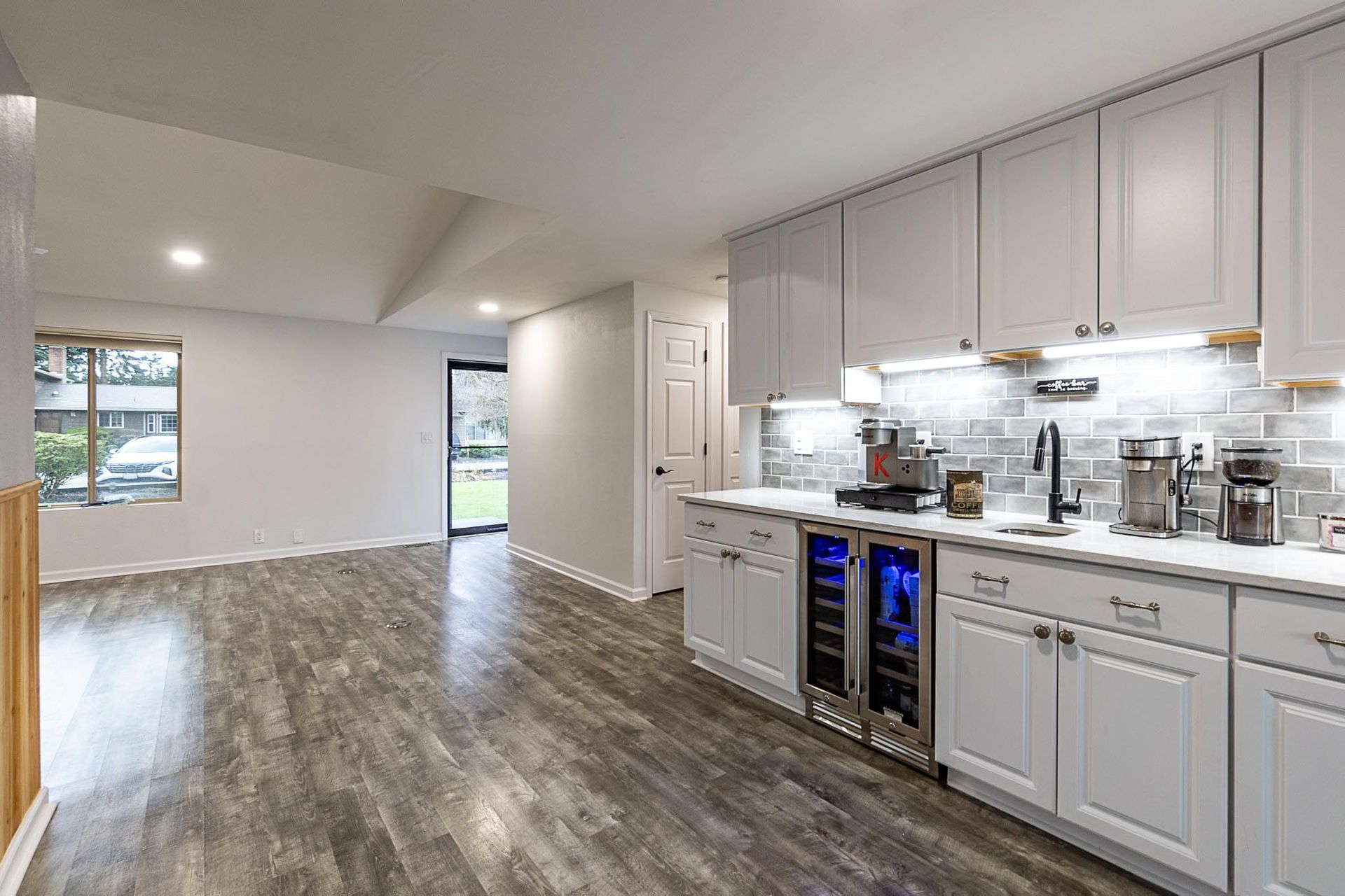 A kitchen with white cabinets , stainless steel appliances , and a wine cooler.