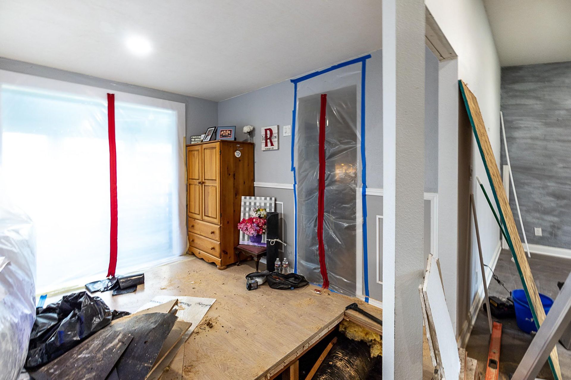 A room is being remodeled with a wooden dresser and a wooden floor.