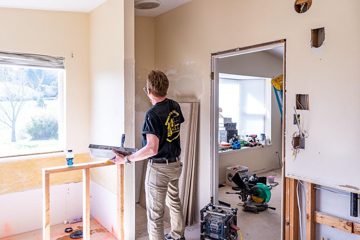 A man is working on a wall in a room.