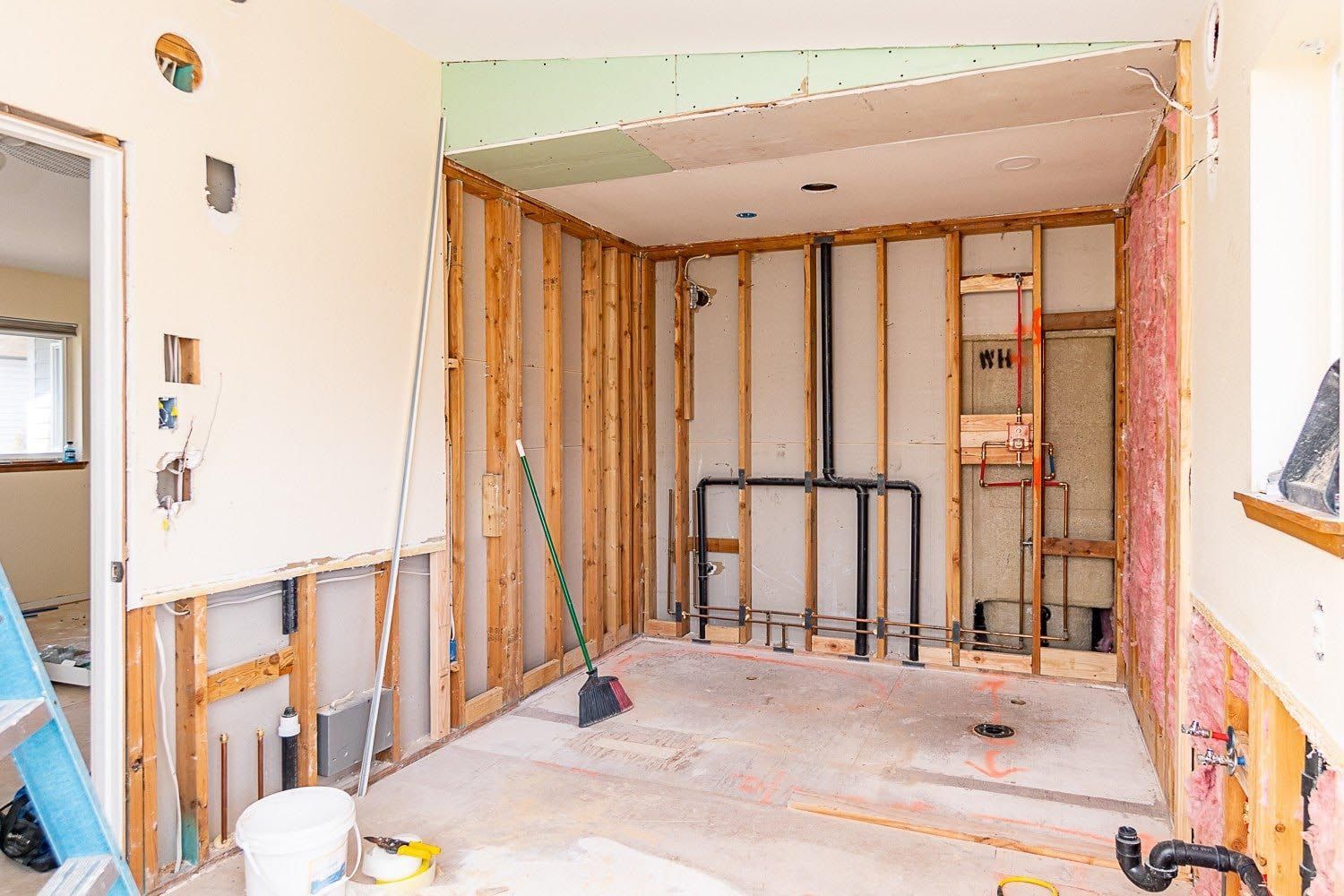 A room that is being remodeled with a broom in it.