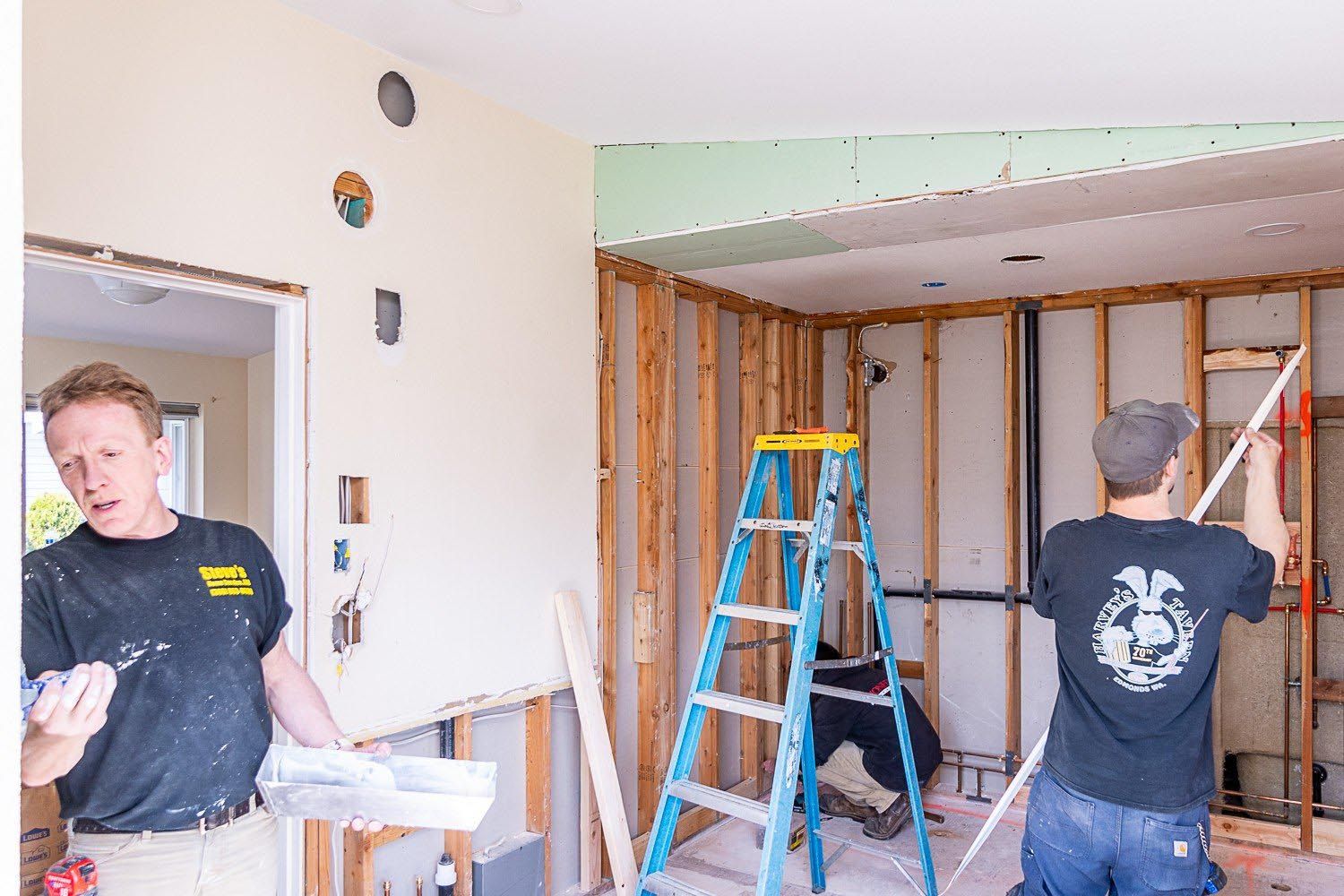 Two men are working in a room with a ladder.