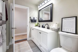 A bathroom with a toilet , sink and mirror.