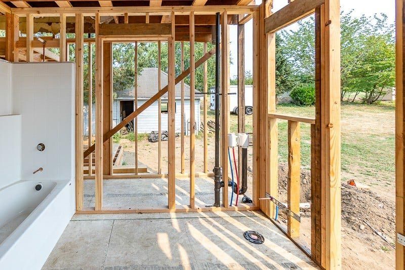 A bathroom under construction with wooden walls and a bathtub.