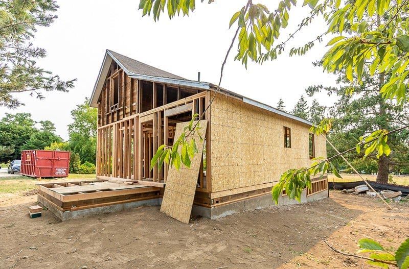 A small house is being built in the middle of a dirt field.