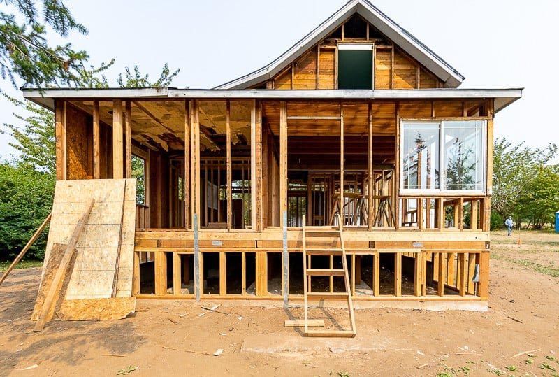 A wooden house is being built in a dirt field.