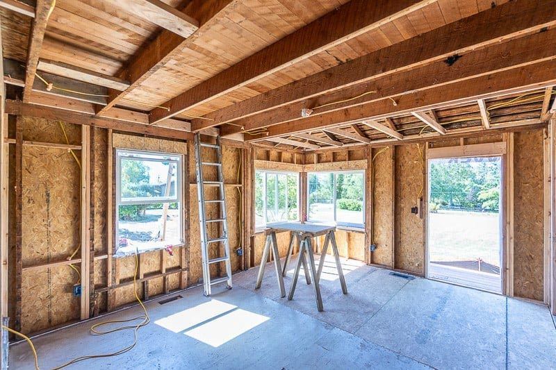 A room in a house under construction with a ladder and a table.