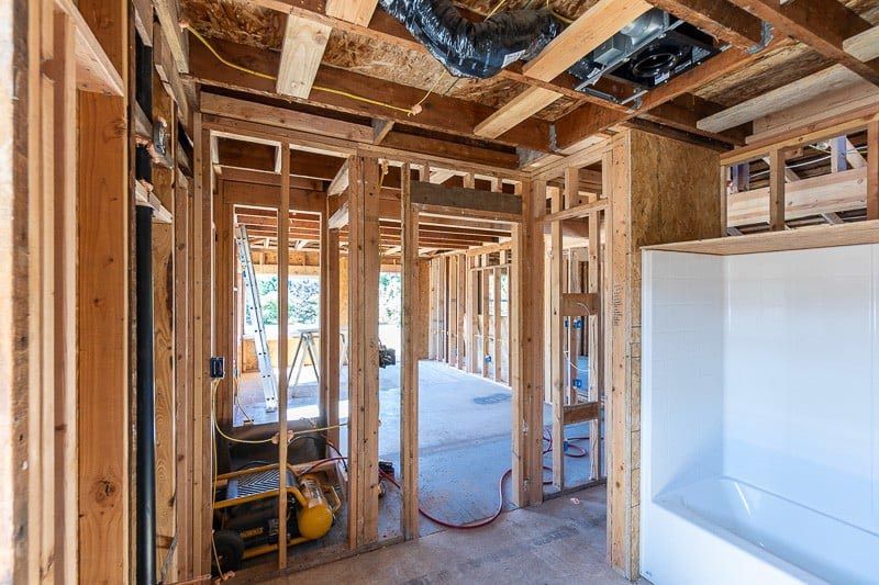 A room in a house under construction with wooden beams and a bathtub.