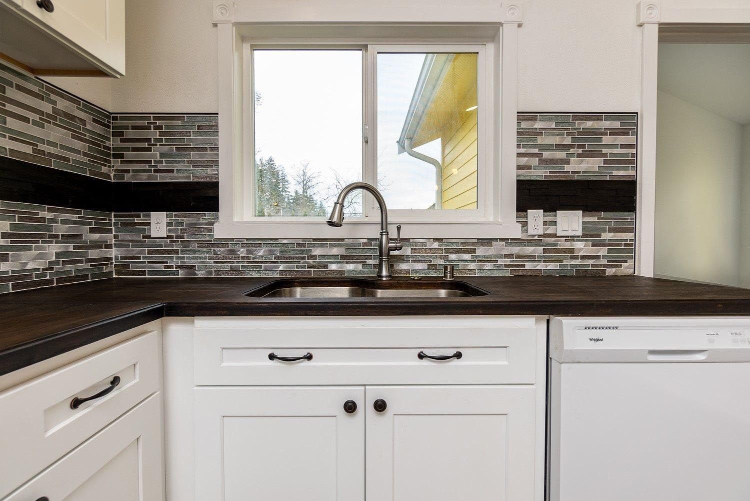 A kitchen with a sink , dishwasher , and window.