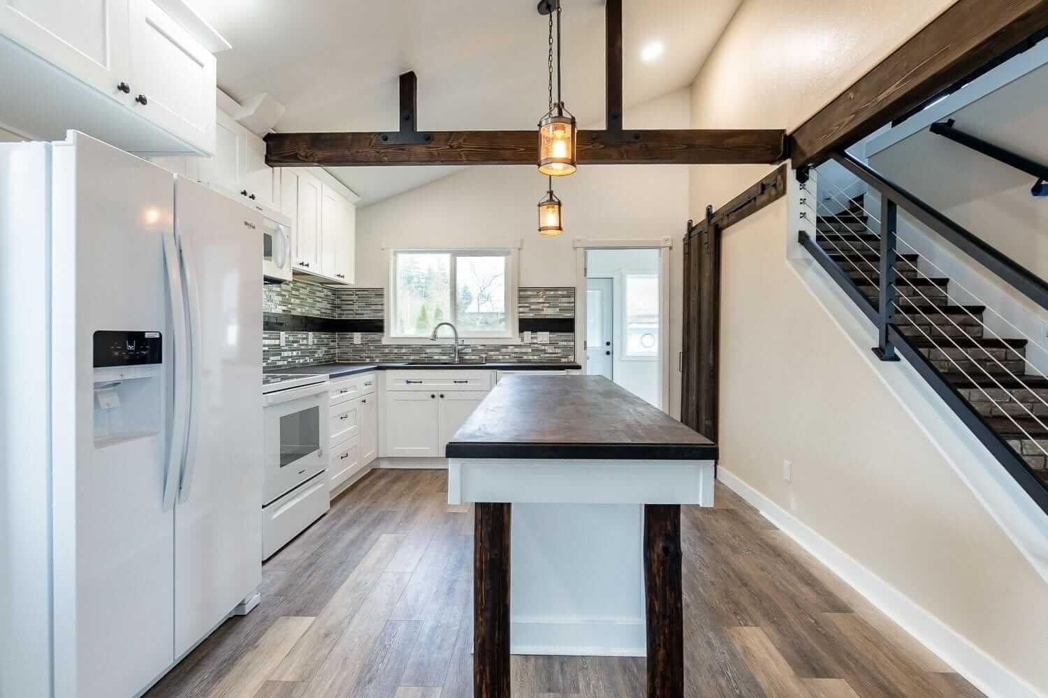 A kitchen with a large island and stairs leading up to the second floor.