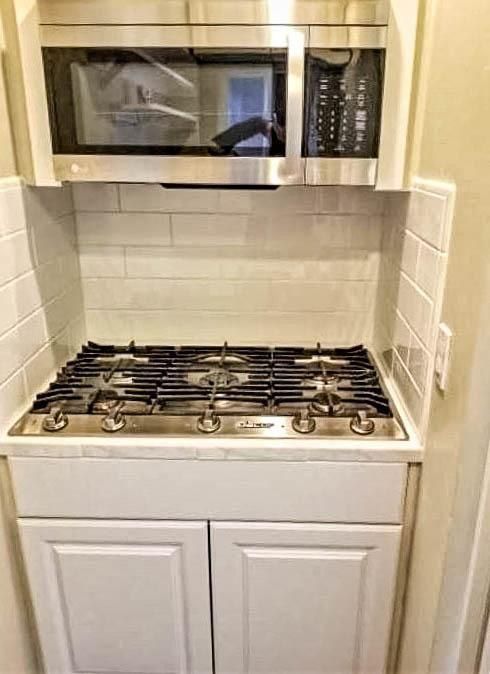 A stove top oven with a microwave above it in a kitchen.