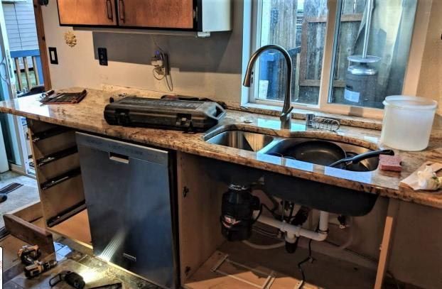 A kitchen with two sinks , a dishwasher , and a window.