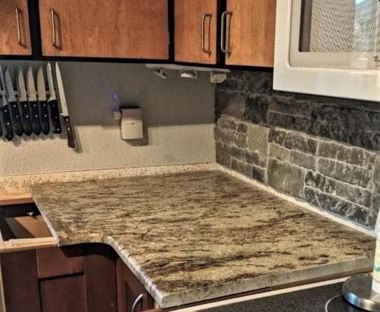 A kitchen with granite counter tops , wooden cabinets , and a microwave.