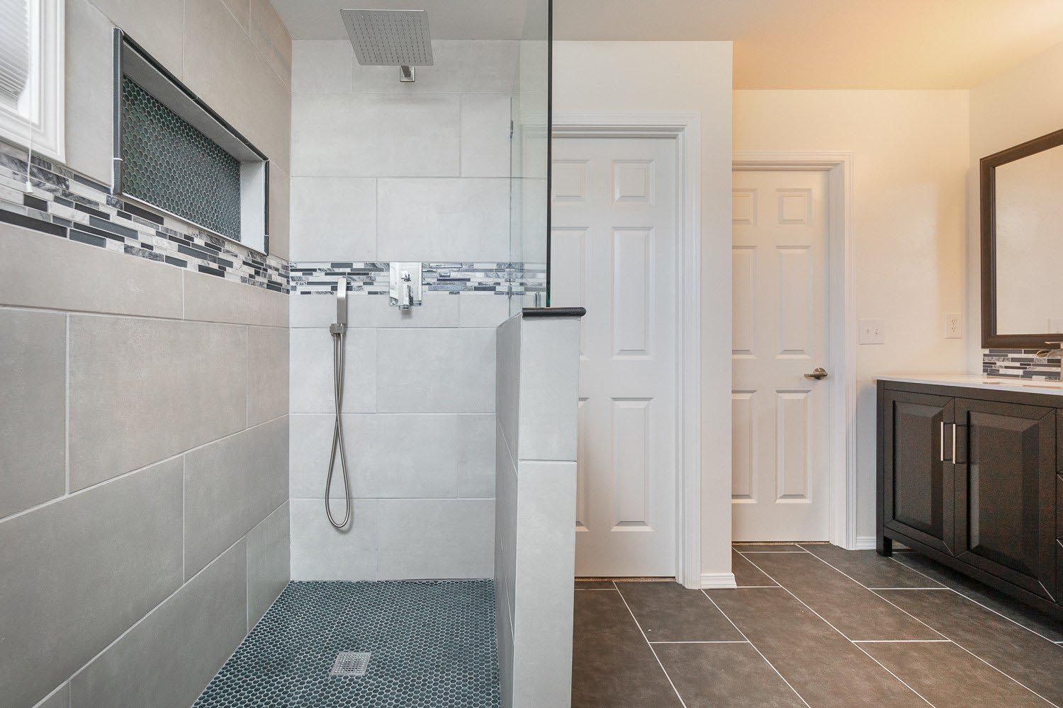 A bathroom with a walk in shower and a sink.