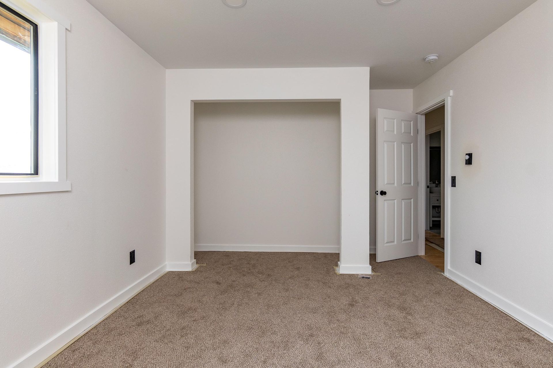 An empty room with a closet and a window.