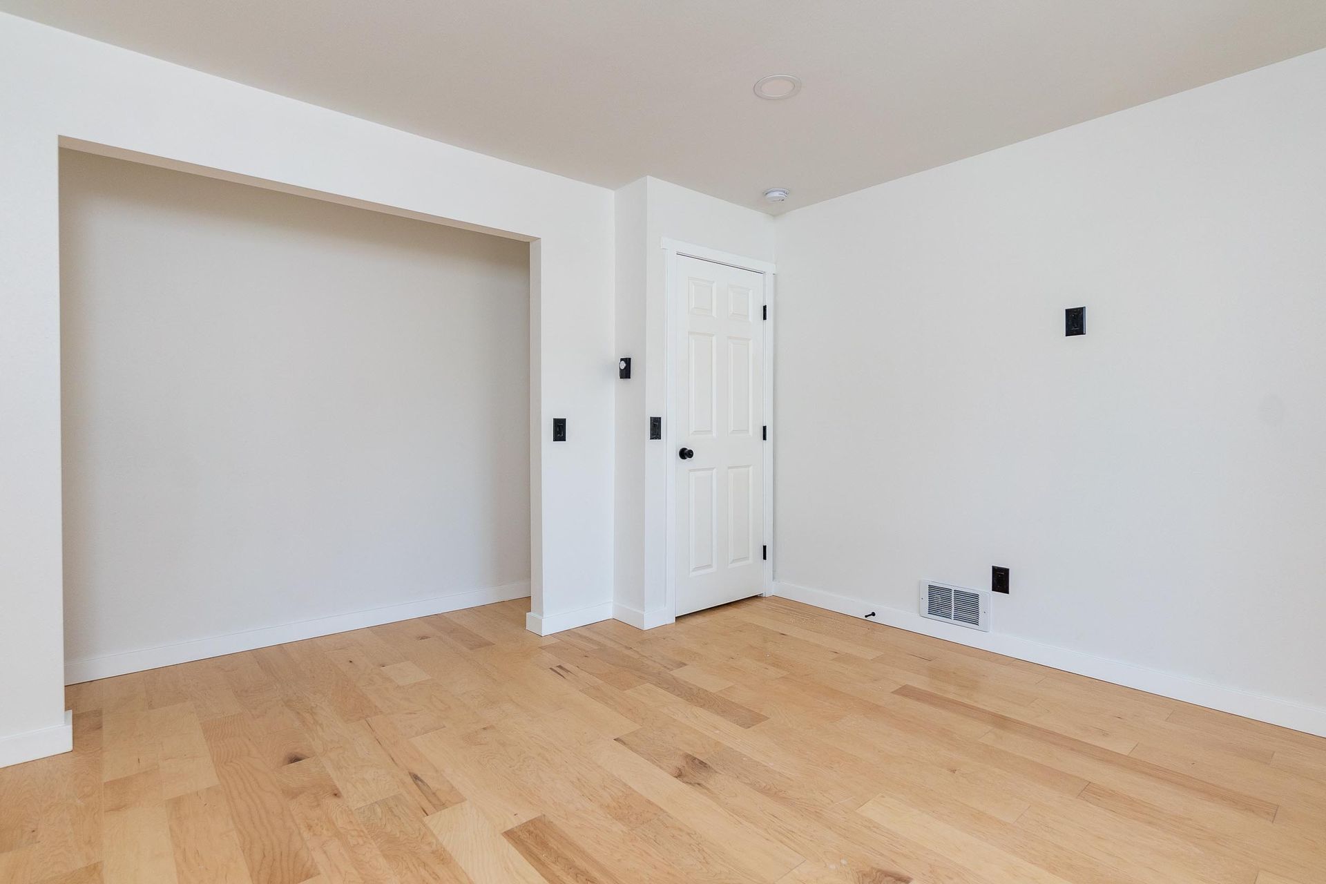 An empty room with hardwood floors and white walls.