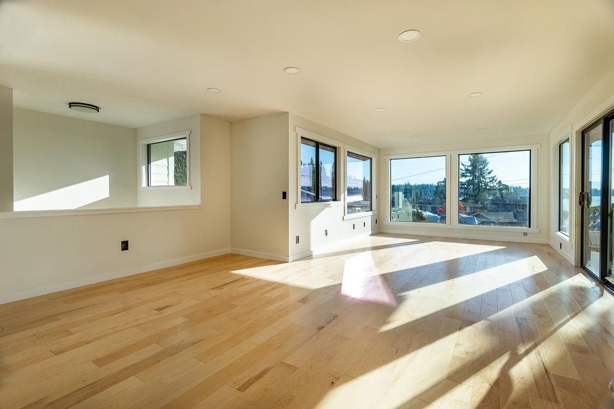 An empty living room with hardwood floors and lots of windows.