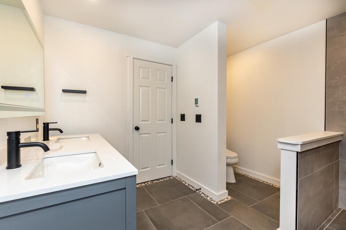 A bathroom with two sinks , a toilet and a mirror.
