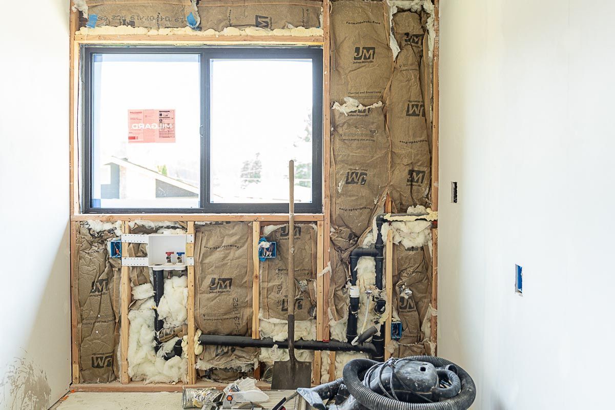A bathroom under construction with a window and pipes.