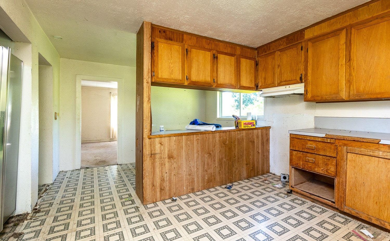 An empty kitchen with wooden cabinets and a tiled floor.