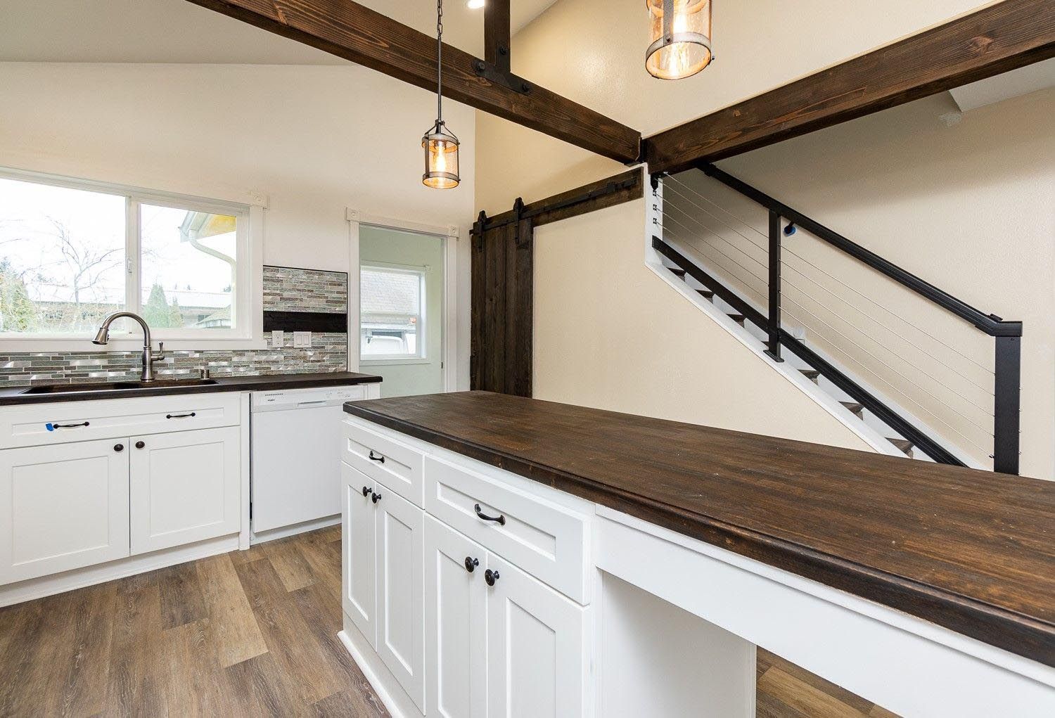A kitchen with white cabinets and a wooden counter top.