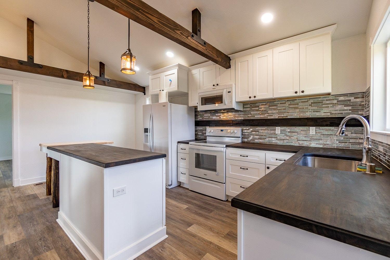 A kitchen with white cabinets , stainless steel appliances , and a large island.