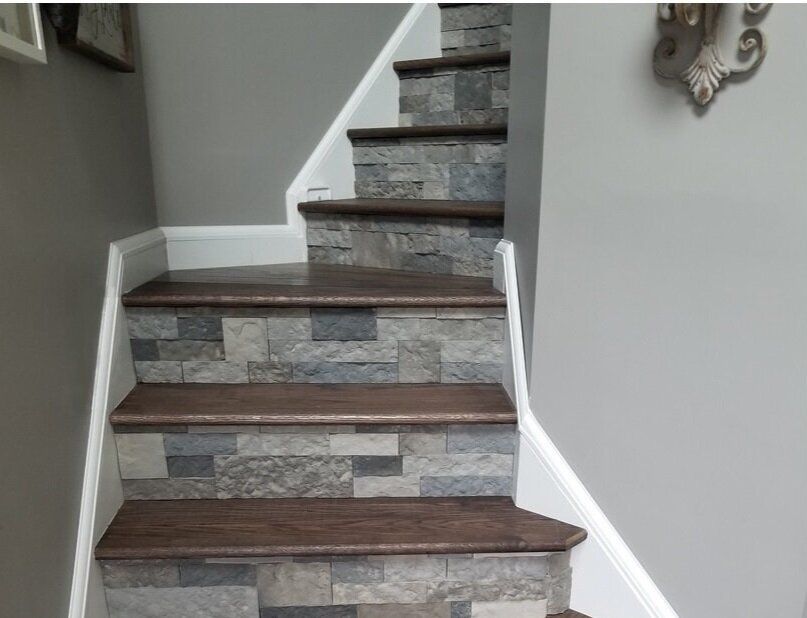 Staircase with dark wood treads and stone-like risers against gray walls. White trim.