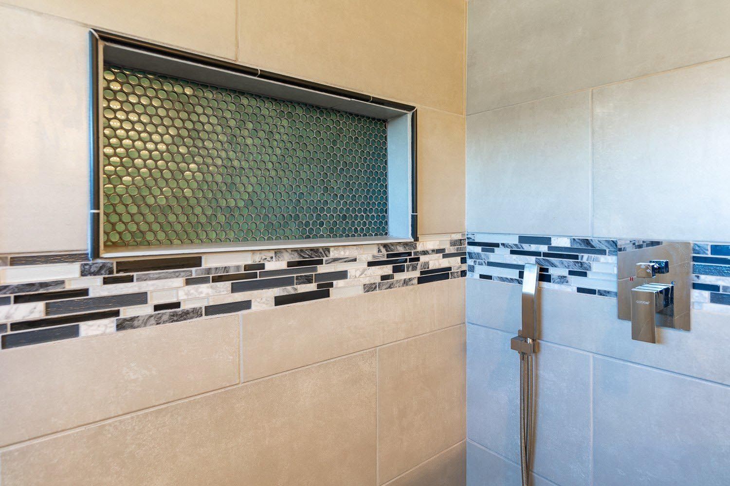 A shower with a tiled wall and a shower head.
