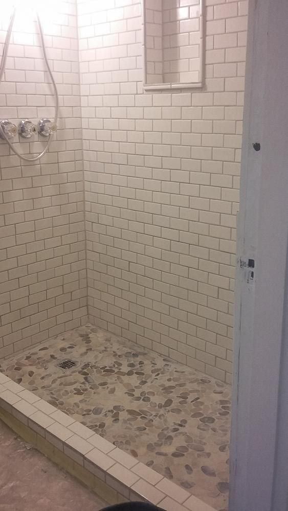 A bathroom with white tiles and a walk in shower.