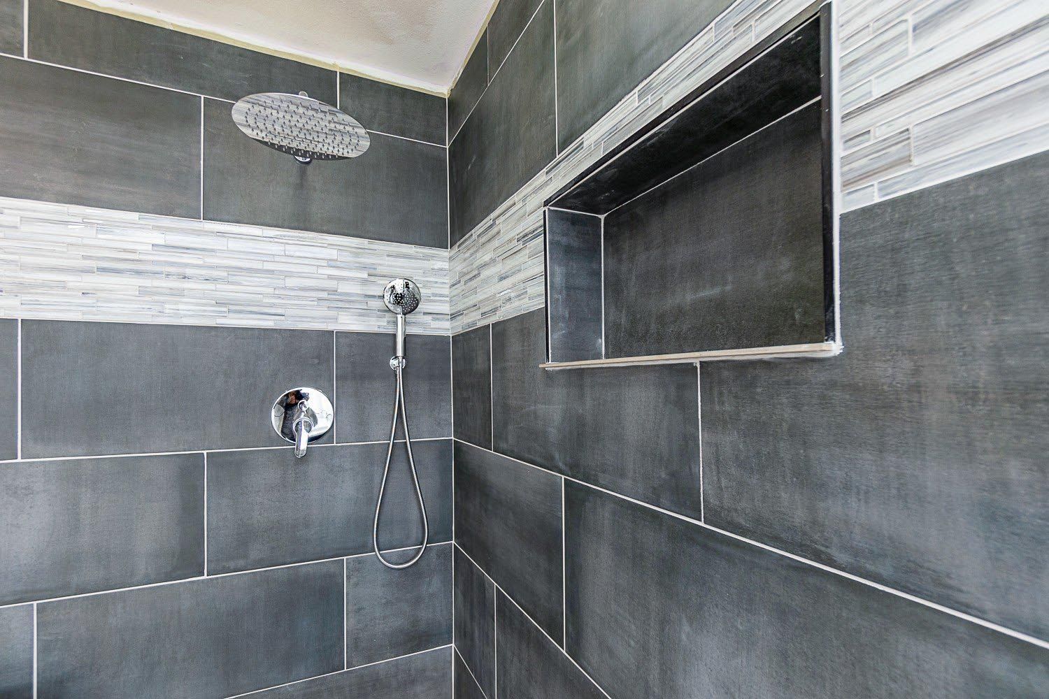 A shower with a shower head and a shelf in the wall.