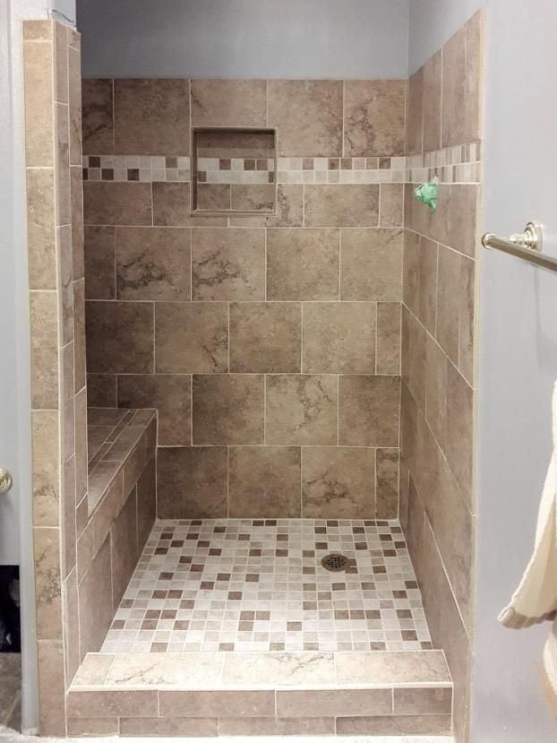 A bathroom with a walk in shower and a bench.