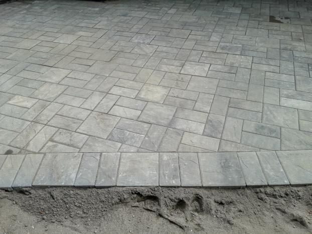 A brick patio is being built in the dirt.