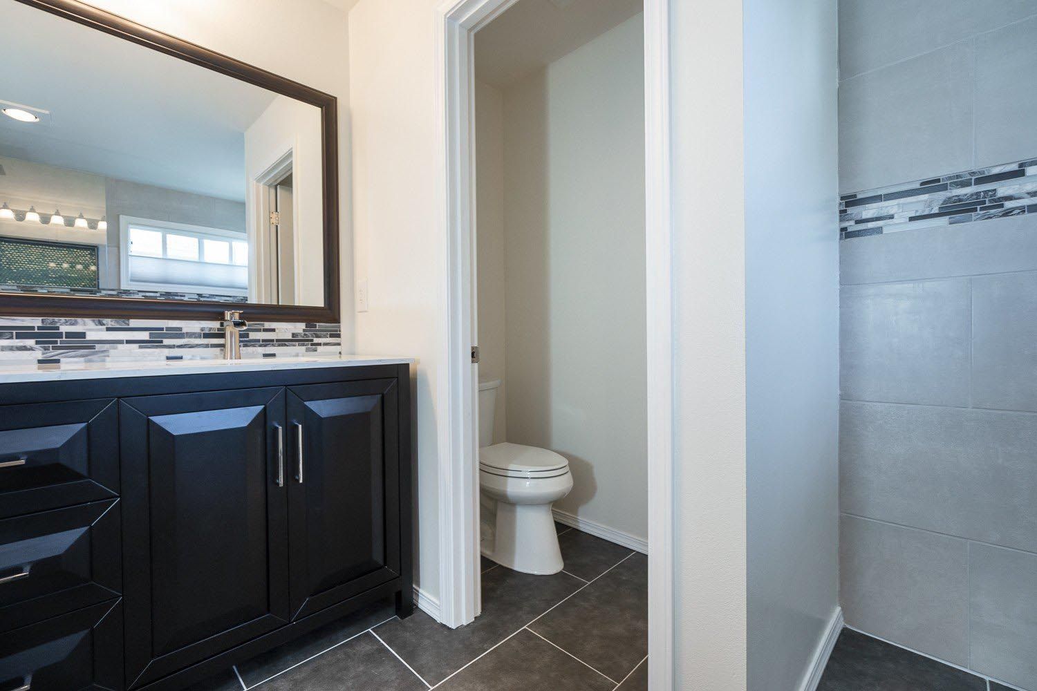 A bathroom with a toilet , sink , mirror and walk in shower.